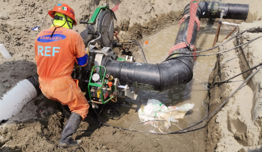 Especialista realizando la termofusión de un codo de tubería PEAD con equipo McElroy durante la instalación de una red hidráulica en un proyecto de infraestructura.